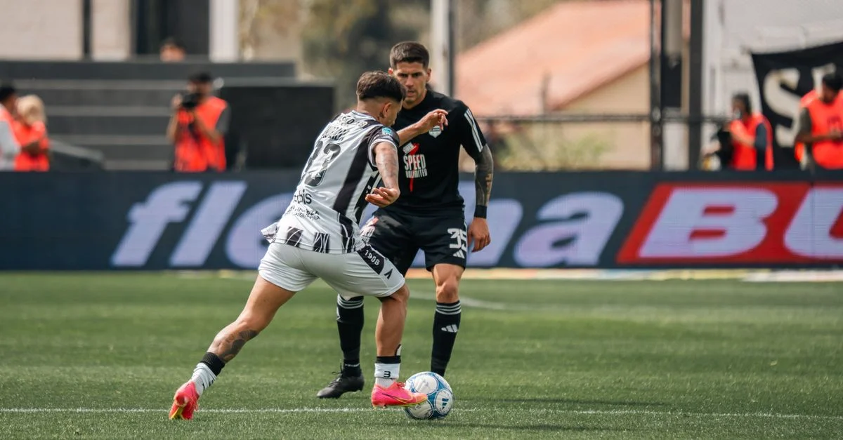 Action intense de football avec deux joueurs s'affrontant sur le terrain lors d'un match professionnel.