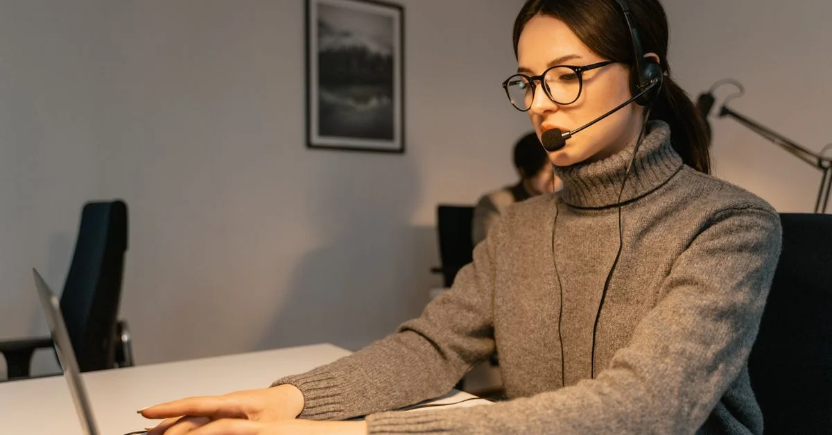 Femme dans un centre d'appels fournissant un support client avec un casque et un ordinateur portable.