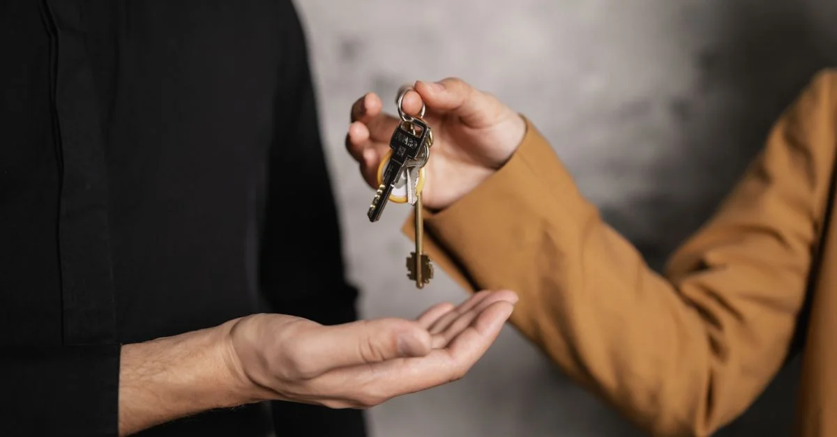 Gros plan détaillé d'une personne donnant des clés à une autre, symbolisant une transaction immobilière.