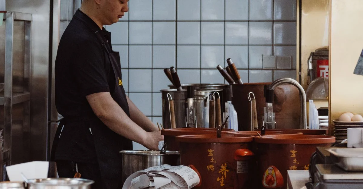 Chef travaillant dans une cuisine chinoise authentique avec des outils et ustensiles de cuisine traditionnels.