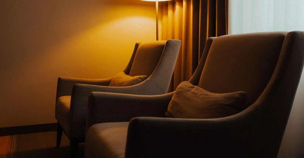 Un intérieur chaleureux avec deux fauteuils et une lampe à la lumière douce, idéal pour se détendre.