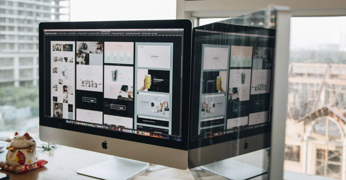 Deux moniteurs sur un bureau, présentant un design web dans un cadre de bureau moderne.