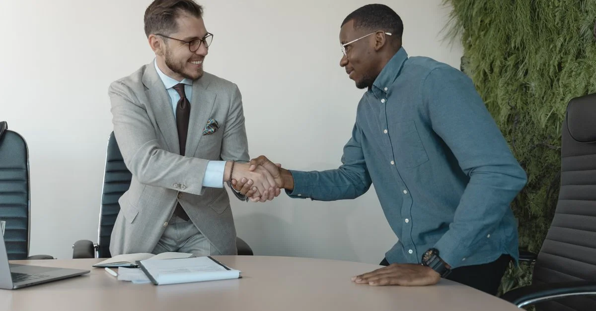 Deux hommes se serrant la main lors d'une réunion professionnelle dans un bureau moderne.