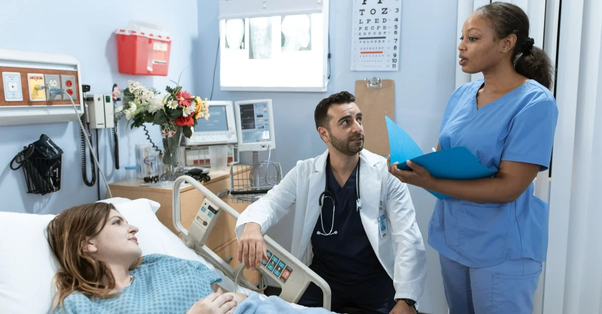 Médecins et infirmières discutant du traitement du patient dans une chambre d'hôpital.