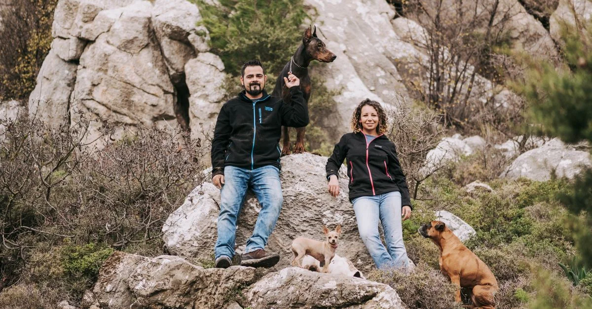 Un couple profite de la randonnée avec leurs chiens sur un terrain rocheux pittoresque, mettant en avant l'aventure et la camaraderie.